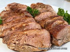 some meat is on a white plate with parsley around the top and bottom part