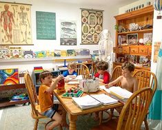 three children sitting at a table with books and toys