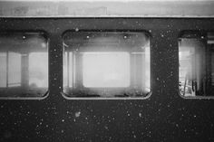 two windows on the side of a train car with snow falling all over them and it's frosting