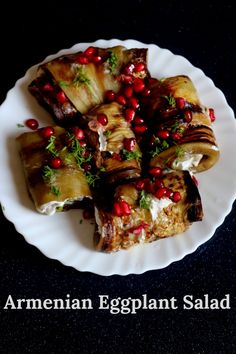 an arrangement of eggplant salad on a white plate with pomegranates