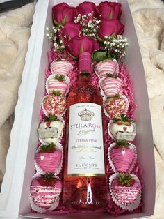 a bottle of wine in a box with pink roses and strawberries on the table