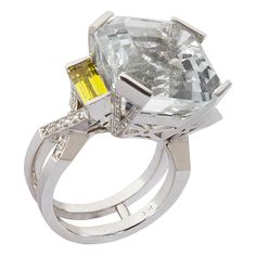 Elegant & Finely detailed Ring centering an Asscher cut Natural White Topaz flanked by 2 yellow beryl (Helidor) baguette; further accented by 82 brilliant round cut diamonds in a beautifully hand crafted 18k white gold statement ring from the Coach House Workshop; The Square Asscher cut Topaz; approx. total weight 27.06 carat has rolling sparkle, flanked by 2 yellow beryl (Helidor) baguette; approx. 1.05 carat; further enhanced with 82 round brilliant cut diamonds, approx. total weight 0.50 carat, G/H, VS. Prong, channel and bead setting; Stamped: 18k; approx. weight of ring: 17.42 grams; Height at top: 14mm; Width at top: 16mm; Ring size 7.25 and sizable. The ring is in excellent condition and was recently professionally cleaned and polished. Illuminate your look with Timeless Beauty with Asscher Cut Ring, White Diamond Rings, Diamond Gold Ring, White Gold Diamond Earrings, Platinum Diamond Rings, Coach House, Gold Statement Ring, Gold Cocktail Ring, Pendant Watches