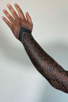 a man's arm with tattoos on it and his hand extended out to the side