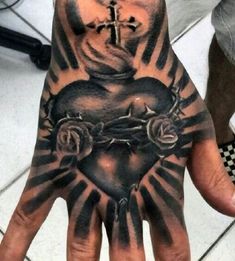 a person's hand with a heart and cross tattooed on the middle of it