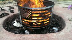 a fire pit with an american flag design on it and trash cans in the background