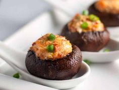 three stuffed mushrooms with cheese and green onions on a white plate, ready to be eaten