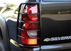 the rear end of a black truck with silver lettering on it's tail lights