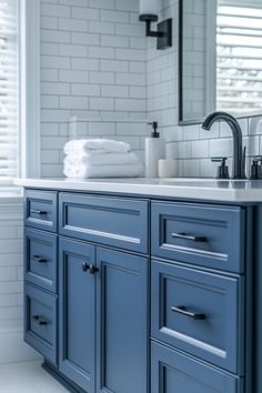 a bathroom with blue cabinets and white tile