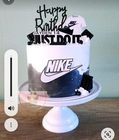 a white and black nike birthday cake on top of a wooden table with the words happy birthday next to it