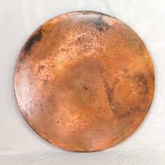 an old metal plate sitting on top of a white sheet