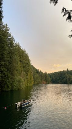 a small boat floating on top of a lake surrounded by forest