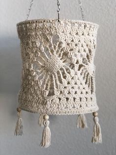 a crocheted lamp shade hanging from a chain with tassels on it