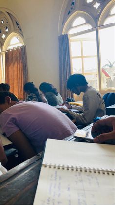 a group of people sitting at desks with notebooks