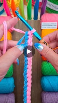 two hands holding crochet hooks in front of colorful yarn