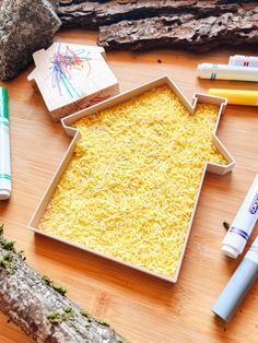 a wooden table topped with yellow rice and markers