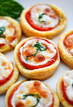 small pizzas with cheese and tomato sauce on them sitting on a white platter