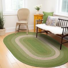 a living room with a green rug, chair and potted plant in the corner