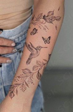 a woman's arm with a hummingbird and flowers tattoo on the left forearm