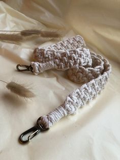 two crocheted leashes are laying on a white sheet next to some feathers