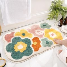 a bathroom rug with flowers on it and a person's feet in the bathtub