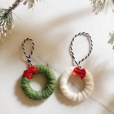 two christmas wreath ornaments hanging from twine