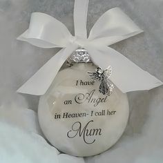 a glass ornament with a white ribbon and a silver bee on it that says i have an angel in heaven, i call her mom