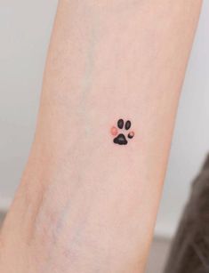 a small paw tattoo on the ankle with pink and black dots in between it's paws