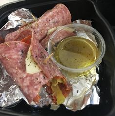 there is a tray with some meats and sauce on the foil wrapper next to it