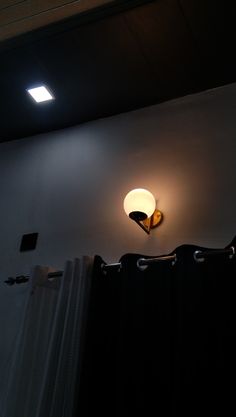 a light that is on the side of a wall next to a curtain in a room