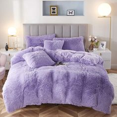 a bed with purple comforters and pillows in a room