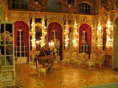 an elaborately decorated room with chairs and a piano in the center is lit by candles