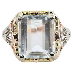 An Art Deco period aquamarine solitaire filigree ring with a unique tri colored 14 karat gold mounting. Centered by a 4.00 carat sky blue aquamarine secured by four polished yellow gold prongs. The die struck mounting complemented by floral and scroll work decoration in rose, white, and yellow gold. Hallmarked, and tested as 14 karat gold. Measurements: 15mm across the top from north to south with a rise of 6mm. Weight: 4.2 grams. Size: 8 US, complimentary resizing is available. Scroll Work, Art Deco Period, Filigree Ring, Aquamarine Blue, Solitaire Ring, Estate Jewelry, Rings Statement, Aquamarine, Or Rose