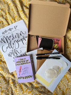 an open box on a bed with some writing and papers in it, including notebooks