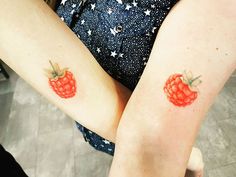 two people with matching tattoos on their arms, one has a red berry on the other