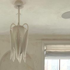 a chandelier hanging from the ceiling in a room with white walls and curtains