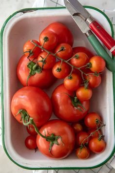 a bowl filled with lots of tomatoes next to a pair of scissors