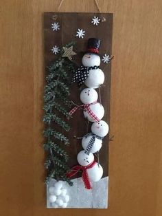 a snowman hanging on the side of a wooden door with christmas decorations around it