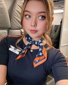 a woman wearing an orange and black neck tie sitting on top of an airplane seat