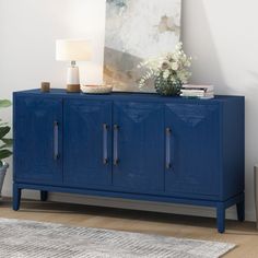 a blue sideboard with two doors and a painting on the wall in front of it