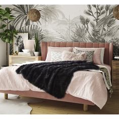 a bedroom with pink bedding and tropical wallpaper