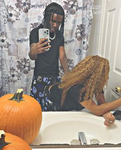 a woman taking a selfie in front of a mirror with pumpkins on the counter