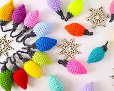 crocheted christmas lights are arranged on a white surface, with snowflakes in the background