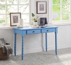 a blue desk with two drawers in front of a window and pictures on the wall