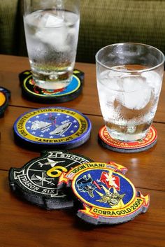 four coasters with different designs on them sitting on a wooden table next to a glass of water