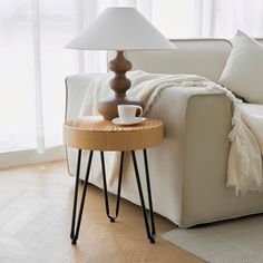 a white couch sitting next to a table with a cup on it