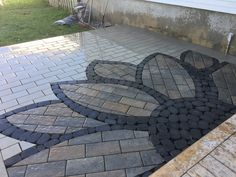 an outdoor patio with cobblestone pavers and brick edging in the shape of a flower