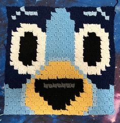 a close up of a blue and yellow blanket with an animal face on it's side