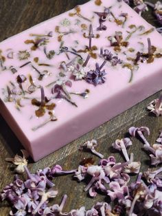 a bar of soap sitting on top of a wooden table covered in purple and white flowers