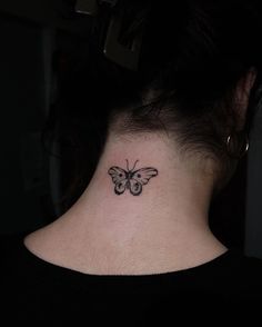 a woman's neck with a small butterfly tattoo on the back of her neck