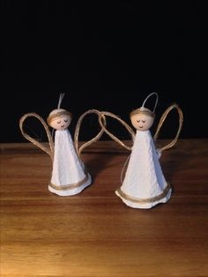 two little angel figurines sitting on top of a wooden table